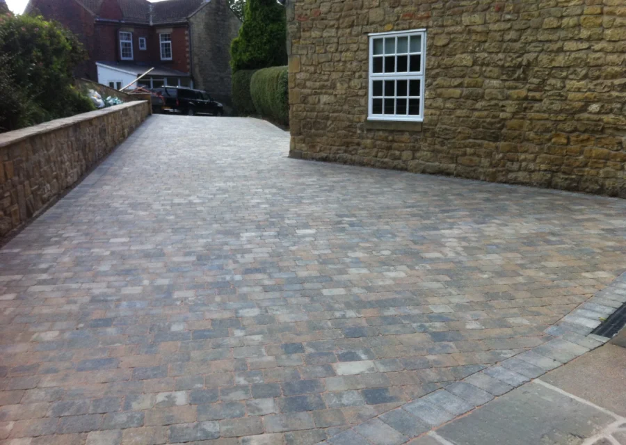 Tumbled block paving driveway running alongside a stone built cottage
